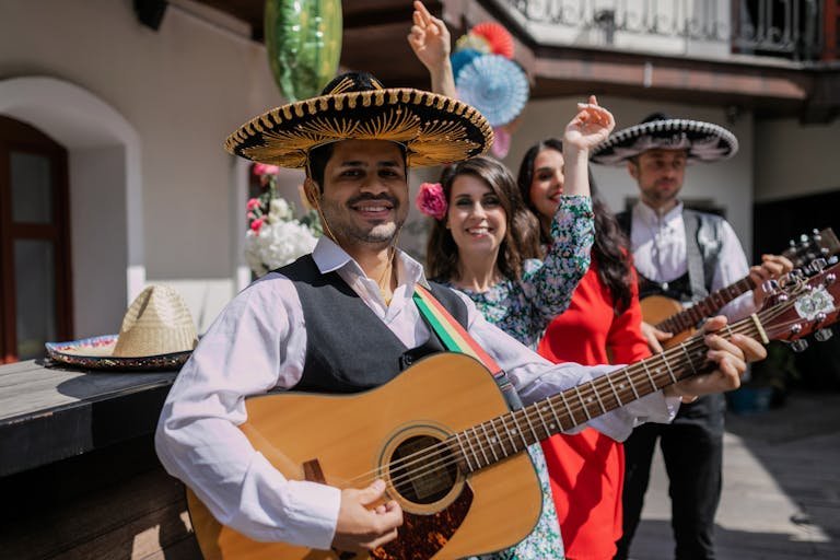 Lively Mexican musicians with guitars in colorful outfits, celebrating a festival.